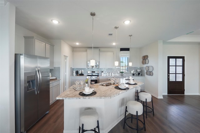 11034 Moon Light Dr, Needville, TX 77461 - kitchen featuring appliances with stainless steel finishes, a sink, dark wood-style flooring, backsplash, and a kitchen island with sink
