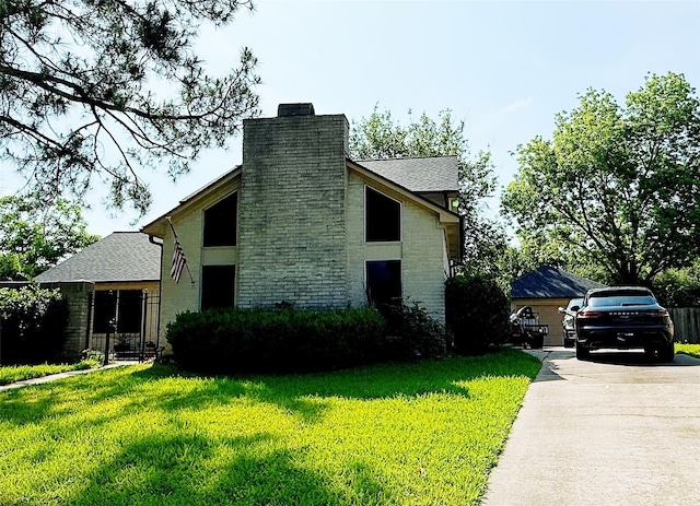 view of front of home featuring a chimney, a front yard, driveway, and roof with shingles