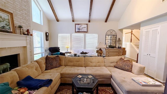 living area featuring high vaulted ceiling, stairs, a tile fireplace, and beamed ceiling