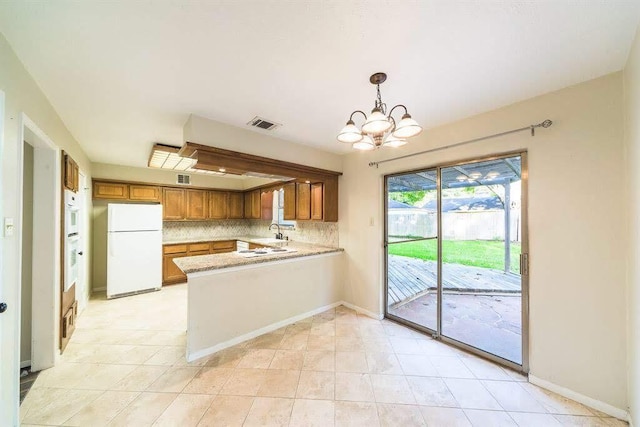 2707 Williams Grant St, Sugar Land, TX 77479 - kitchen featuring freestanding refrigerator, brown cabinets, a peninsula, a chandelier, and light countertops