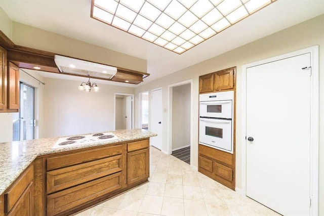 2707 Williams Grant St, Sugar Land, TX 77479 - kitchen featuring brown cabinets, white appliances, a chandelier, a peninsula, and light stone countertops