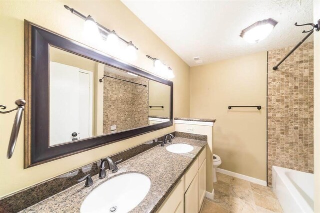 2707 Williams Grant St, Sugar Land, TX 77479 - bathroom with toilet, stone tile floors, double vanity, baseboards, and washtub / shower combination