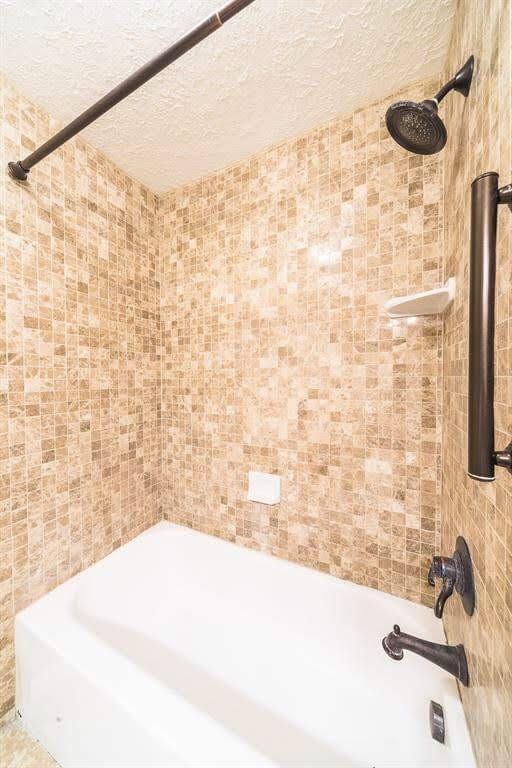 2707 Williams Grant St, Sugar Land, TX 77479 - full bath featuring bathing tub / shower combination, tile walls, and a textured ceiling