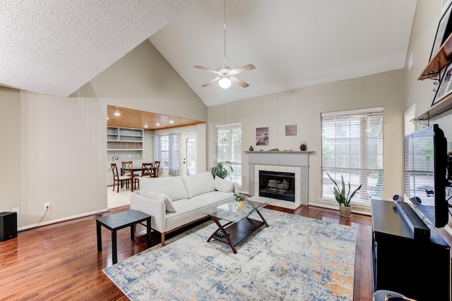 12911 Peach Meadow Dr, Cypress, TX 77429 - living area with wood finished floors, healthy amount of natural light, a tiled fireplace, ceiling fan, and high vaulted ceiling