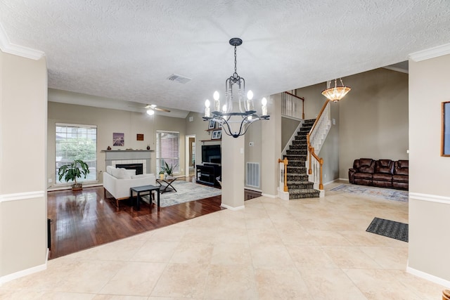 12911 Peach Meadow Dr, Cypress, TX 77429 - tiled living area featuring a chandelier, a tile fireplace, stairs, a textured ceiling, and ceiling fan