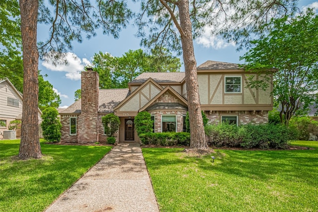 715 Cheltenham Dr, Katy, TX 77450 - tudor home featuring brick siding, stucco siding, a front lawn, a chimney, and central AC