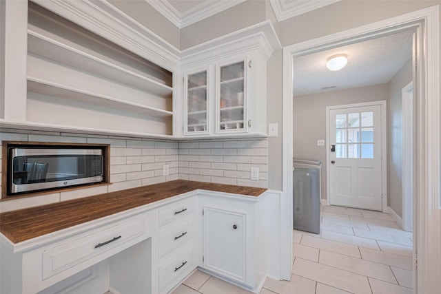 715 Cheltenham Dr, Katy, TX 77450 - kitchen featuring stainless steel microwave, decorative backsplash, light tile patterned floors, white cabinets, and ornamental molding