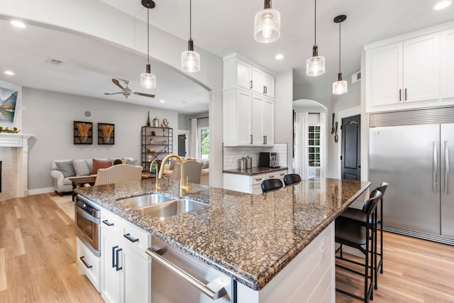 4810 Pine Wood Meadows Ln, Spring, TX 77386 - kitchen featuring appliances with stainless steel finishes, a sink, arched walkways, a kitchen island with sink, and ceiling fan