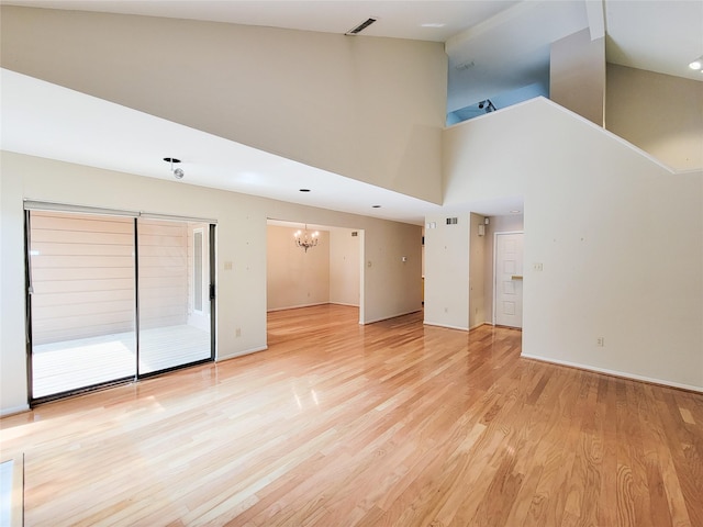 7910 Woodway Dr, Houston, TX 77063 - unfurnished living room featuring a chandelier, light wood finished floors, a towering ceiling, and baseboards