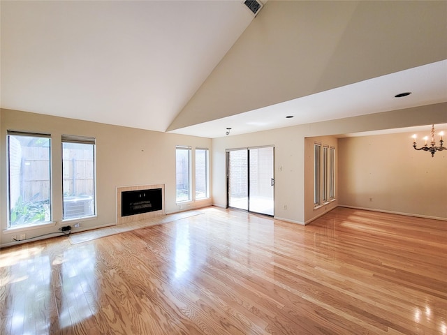7910 Woodway Dr, Houston, TX 77063 - unfurnished living room featuring a chandelier, light wood-type flooring, high vaulted ceiling, a tiled fireplace, and baseboards