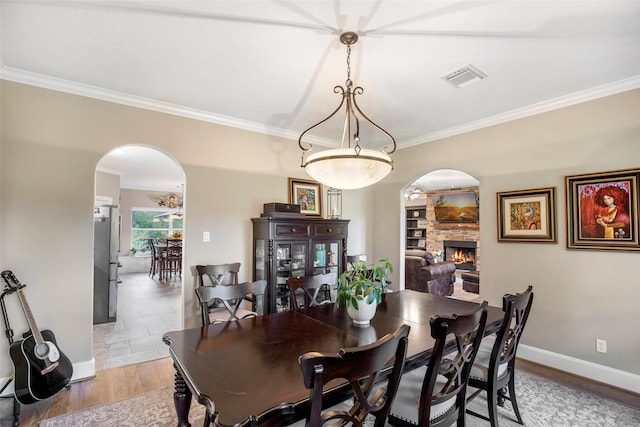 3315 E Bayou Dr, Shoreacres, TX 77571 - dining area featuring arched walkways, crown molding, a fireplace, and light wood-style flooring