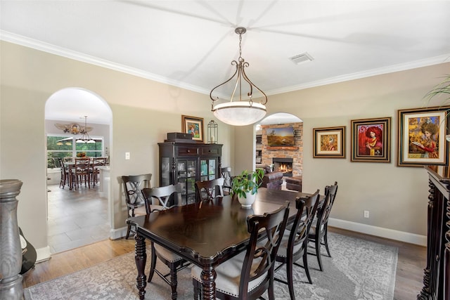 3315 E Bayou Dr, Shoreacres, TX 77571 - dining room featuring arched walkways, ornamental molding, a stone fireplace, and wood finished floors