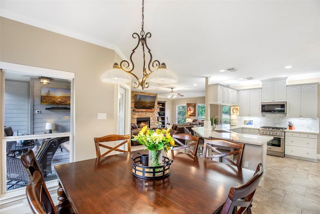 3315 E Bayou Dr, Shoreacres, TX 77571 - dining area featuring crown molding, a fireplace, light stone finish flooring, recessed lighting, and a chandelier
