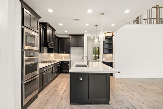 28946 Parker Ridge Dr, Katy, TX 77494 - kitchen featuring a sink, appliances with stainless steel finishes, backsplash, light countertops, and a kitchen island with sink