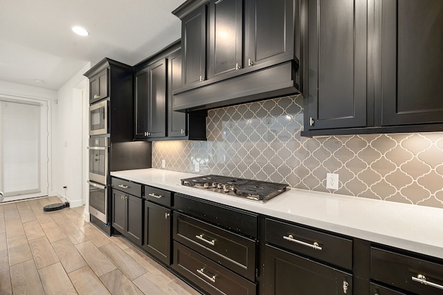 28946 Parker Ridge Dr, Katy, TX 77494 - kitchen with under cabinet range hood, stainless steel appliances, light countertops, backsplash, and recessed lighting