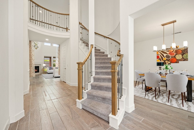28946 Parker Ridge Dr, Katy, TX 77494 - staircase featuring wood finished floors, a high ceiling, baseboards, and a lit fireplace