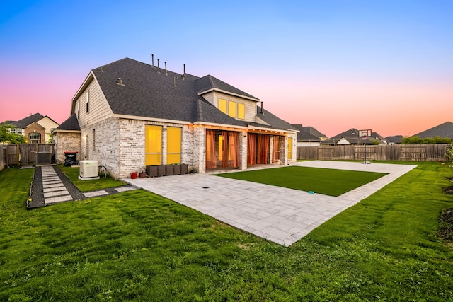 28946 Parker Ridge Dr, Katy, TX 77494 - back of property at dusk with a patio, brick siding, cooling unit, and a shingled roof