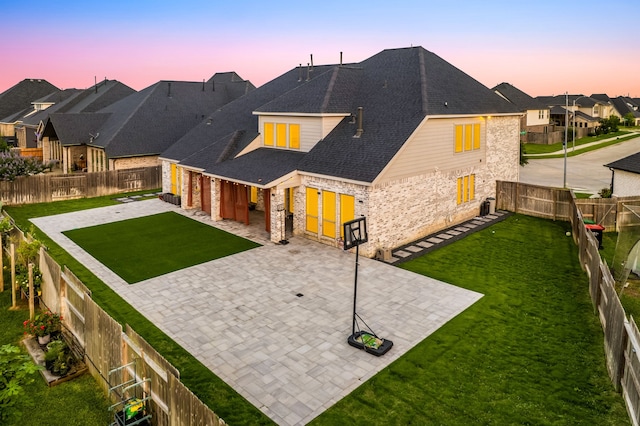 28946 Parker Ridge Dr, Katy, TX 77494 - back of property at dusk featuring stone siding, a patio area, driveway, an attached garage, and a residential view