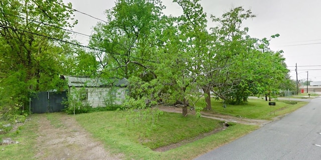 view of yard with fence and dirt driveway
