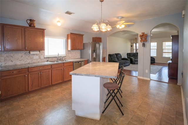 kitchen with appliances with stainless steel finishes, arched walkways, a sink, and healthy amount of natural light