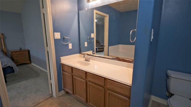 ensuite bathroom featuring toilet, vanity, and baseboards