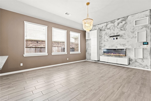 9110 Eckert Rd, Iowa Colony, TX 77583 - unfurnished living room featuring a chandelier, baseboards, wood finished floors, and a large fireplace