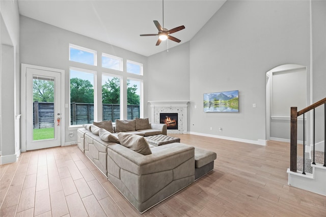 2411 Jitterbug Ln, Katy, TX 77493 - living room with high vaulted ceiling, a ceiling fan, a tile fireplace, light wood-type flooring, and stairs