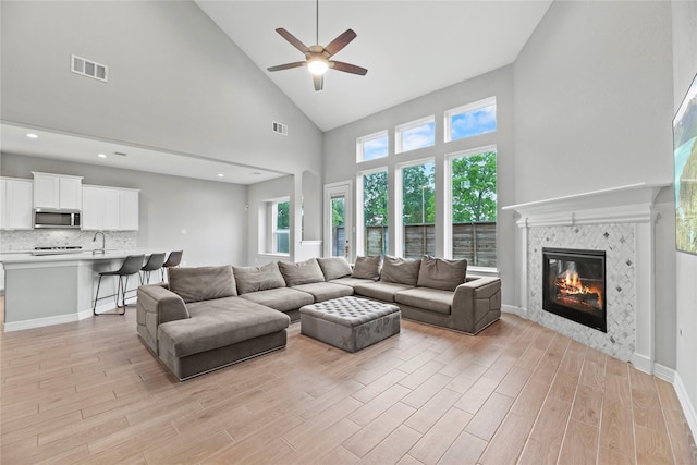2411 Jitterbug Ln, Katy, TX 77493 - living room with light wood-style floors, high vaulted ceiling, ceiling fan, and a tile fireplace