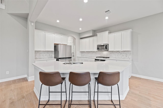2411 Jitterbug Ln, Katy, TX 77493 - kitchen featuring stainless steel appliances, a sink, a center island with sink, backsplash, and a kitchen bar