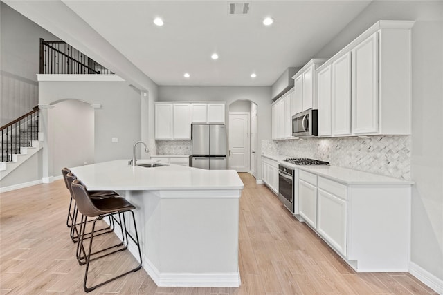 2411 Jitterbug Ln, Katy, TX 77493 - kitchen with arched walkways, appliances with stainless steel finishes, a sink, recessed lighting, and a breakfast bar