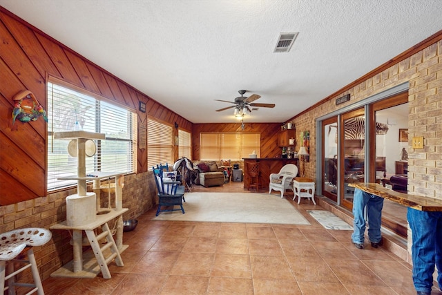 6825 Highland Rd, Santa Fe, TX 77517 - living area with ceiling fan, light tile patterned flooring, wooden walls, a textured ceiling, and crown molding