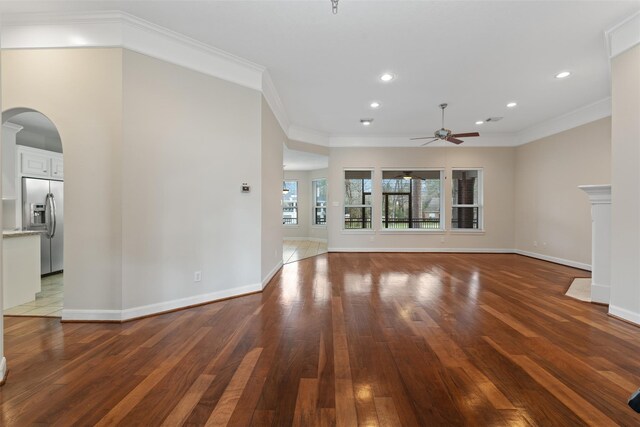 unfurnished living room with ceiling fan, arched walkways, wood-type flooring, recessed lighting, and ornamental molding