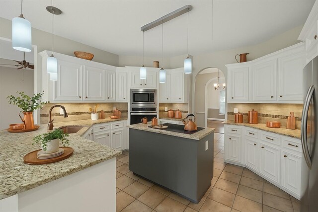 kitchen featuring stainless steel appliances, a sink, backsplash, white cabinetry, and a ceiling fan