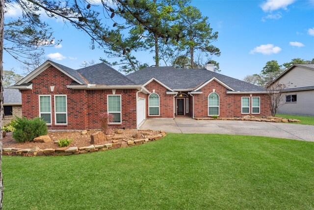 ranch-style home featuring concrete driveway, brick siding, a front yard, and a chimney