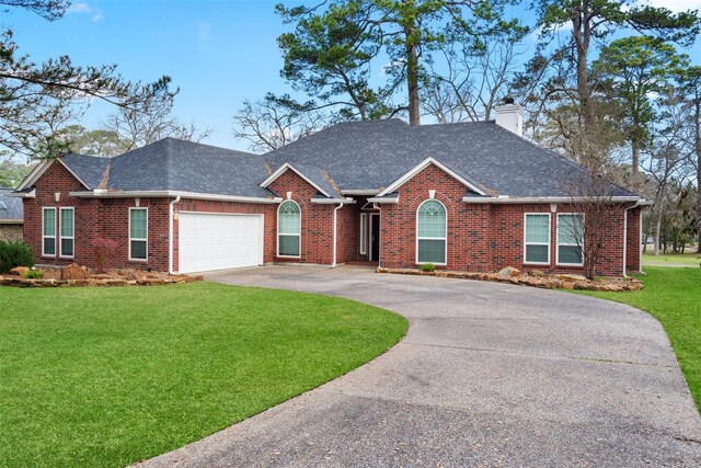 ranch-style house featuring curved driveway, a chimney, a front lawn, and brick siding