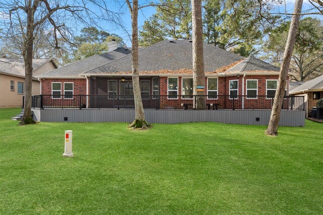 rear view of house featuring brick siding, a chimney, and a lawn