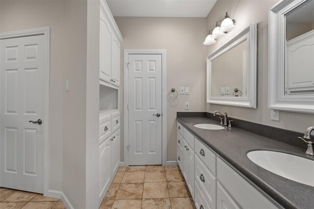 bathroom with baseboards and double vanity