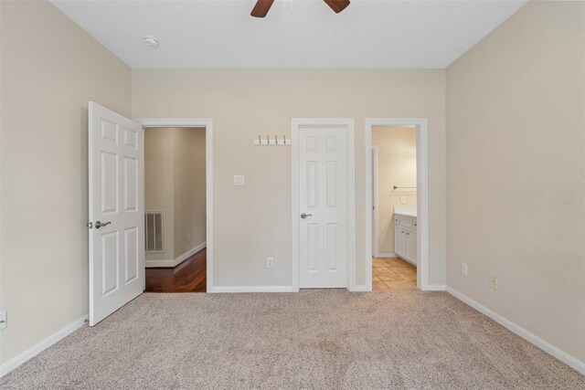 unfurnished bedroom featuring light carpet, baseboards, connected bathroom, and a ceiling fan