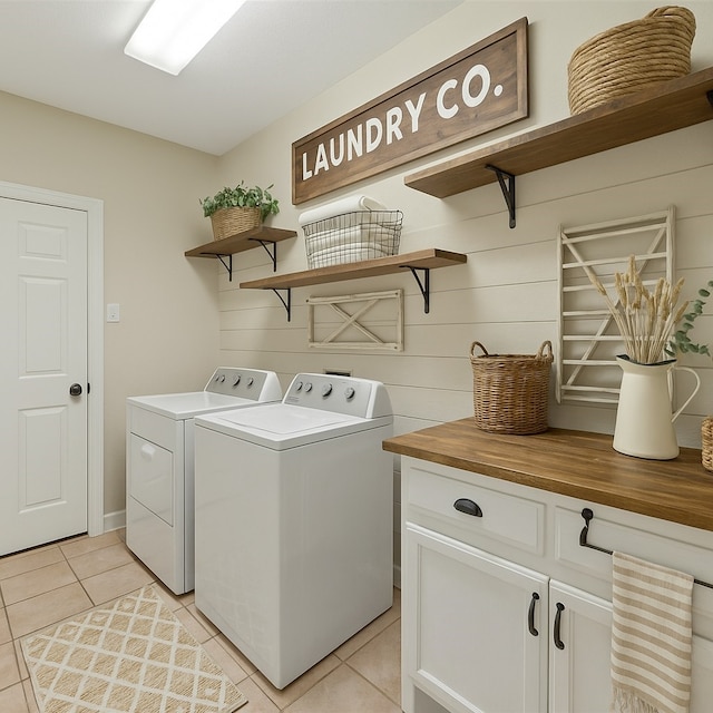 washroom featuring washing machine and clothes dryer, cabinet space, and light tile patterned floors
