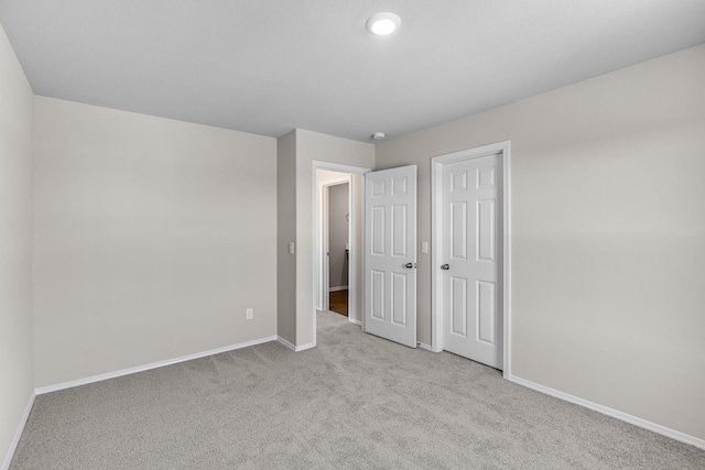 unfurnished bedroom featuring baseboards, light colored carpet, and a closet