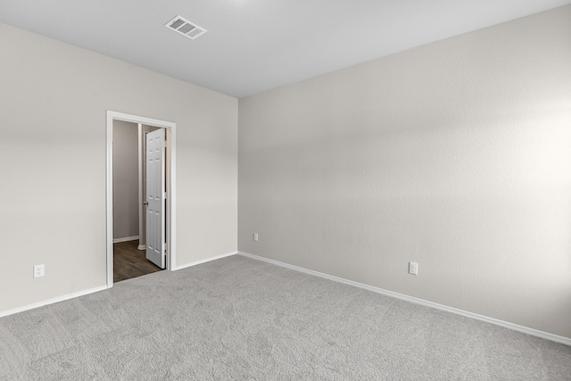 spare room featuring dark colored carpet and baseboards