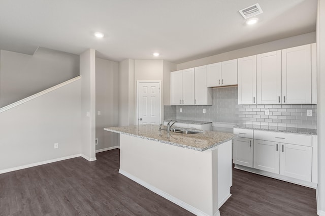 kitchen with a sink, a kitchen island with sink, white cabinetry, tasteful backsplash, and dark wood-style floors