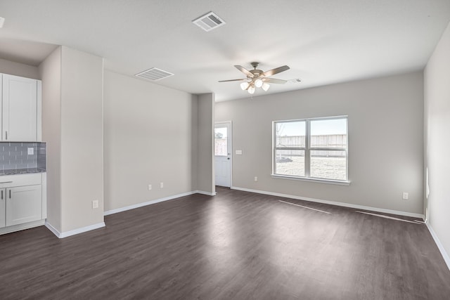 unfurnished living room featuring ceiling fan, dark wood-type flooring, and baseboards
