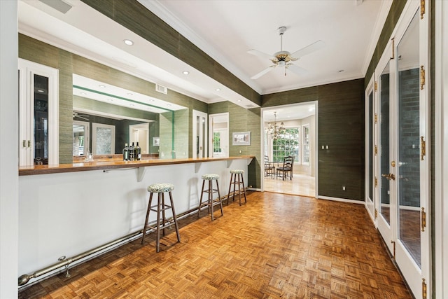 kitchen featuring ornamental molding, butcher block counters, ceiling fan, a breakfast bar area, and a chandelier