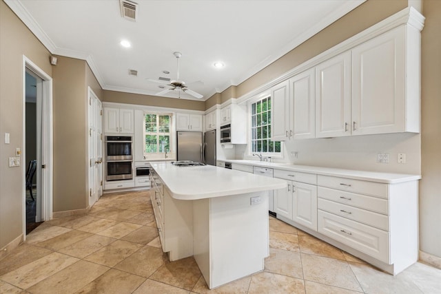 kitchen with crown molding, stainless steel appliances, a center island, white cabinetry, and light countertops