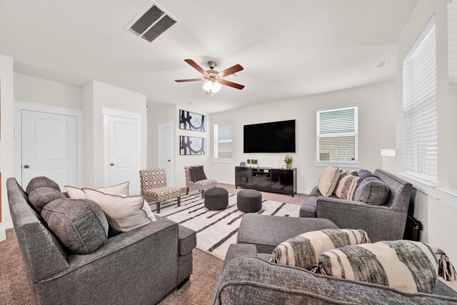 carpeted living area featuring a ceiling fan and plenty of natural light