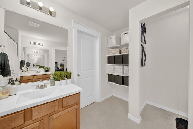 full bath with vanity, tile patterned flooring, and baseboards