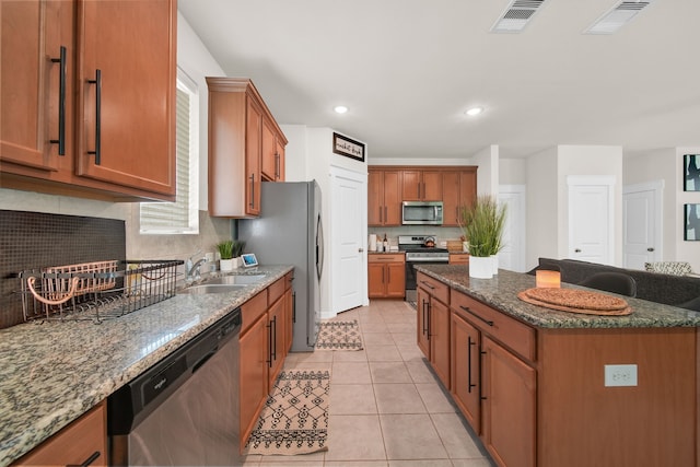 kitchen with appliances with stainless steel finishes, a center island, dark stone countertops, tasteful backsplash, and recessed lighting