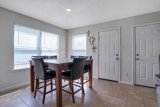 dining room with a textured ceiling, light tile patterned floors, baseboards, and recessed lighting