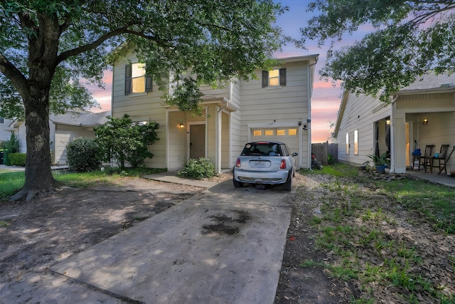 view of front of property featuring an attached garage, concrete driveway, and fence